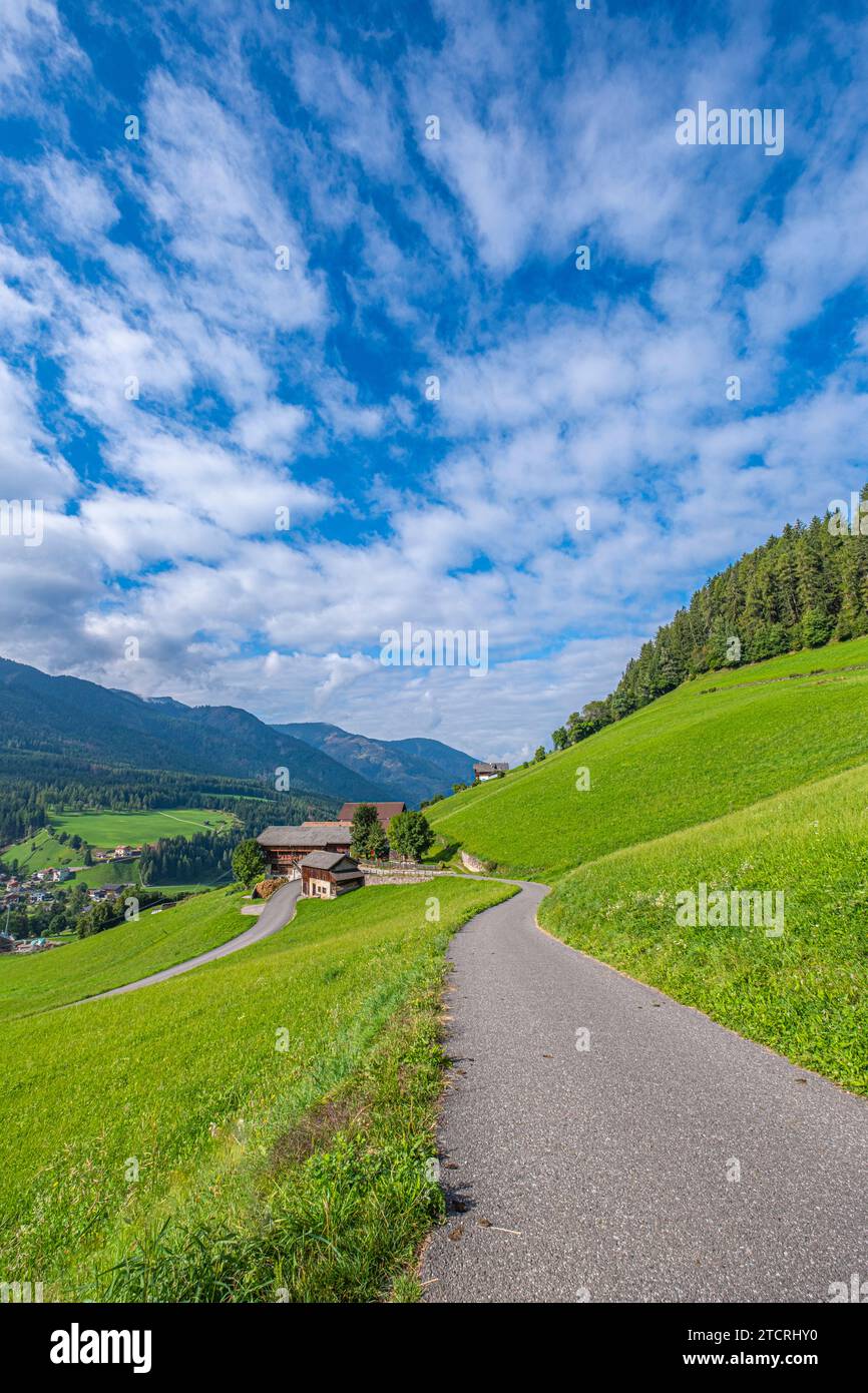 Santa Maddalena, Val di Funes, A quaint house along a winding road, embraced by lush pastures, guides to the majestic, layered Dolomites, an enchantin Stock Photo