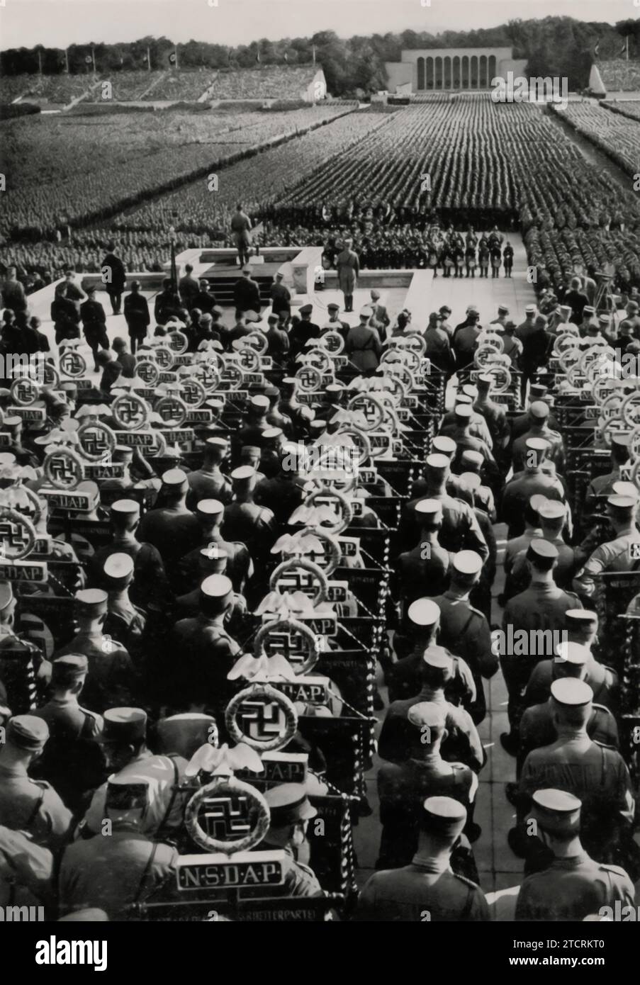 1935 Reichsparteitag (Nazi Party Rally) during the 'Standartenweihe und Totenehrung' (Consecration of the Standards and Commemoration of the Dead), Adolf Hitler is seen making a speech in front of thousands of troops and supporters. This event, combining the solemn remembrance of fallen party members with the ceremonial consecration of military standards, highlights the regime's use of ritual and spectacle. Hitler's address, set against the backdrop of a massive assembly, underscores the orchestrated nature of these rallies in promoting Nazi ideology and reinforcing the Führer's central role. Stock Photo