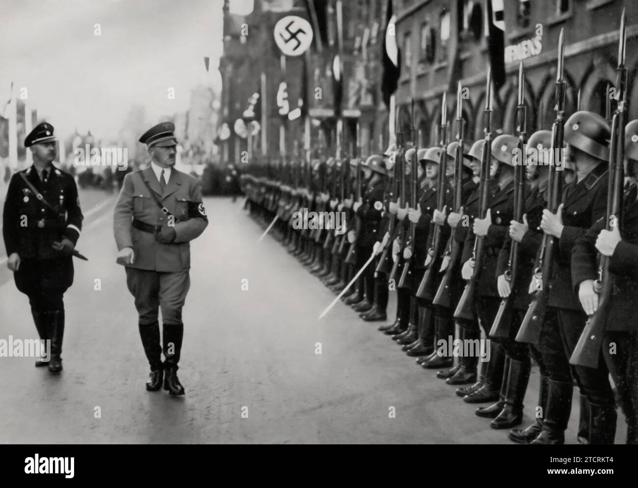 During the 'Parteitag der Freiheit' (Rally of Freedom), Adolf Hitler is seen inspecting the honor company of his Leibstandarte (personal bodyguard unit). This moment captures the ritualistic aspect of the Nazi Party rallies, where Hitler's inspection of his elite troops underscored the themes of loyalty and military precision. The Leibstandarte's role in these ceremonies was a symbol of the close bond between Hitler and his personal guard, reflecting their significance within the Nazi power structure. Stock Photo