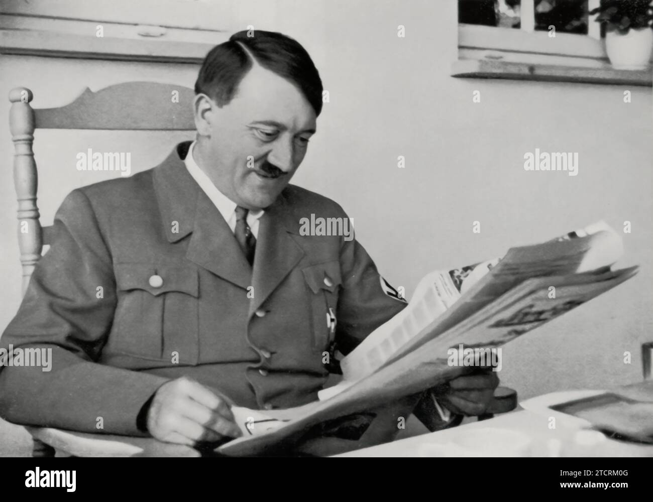 Adolf Hitler is depicted reading a paper, an image titled to suggest he is receiving 'good news.' This portrayal is likely meant to convey a moment of positive development or success, fitting into the broader narrative of his leadership. The act of reading a paper and the implied positive content are used to project an image of a well-informed and triumphant leader. Stock Photo