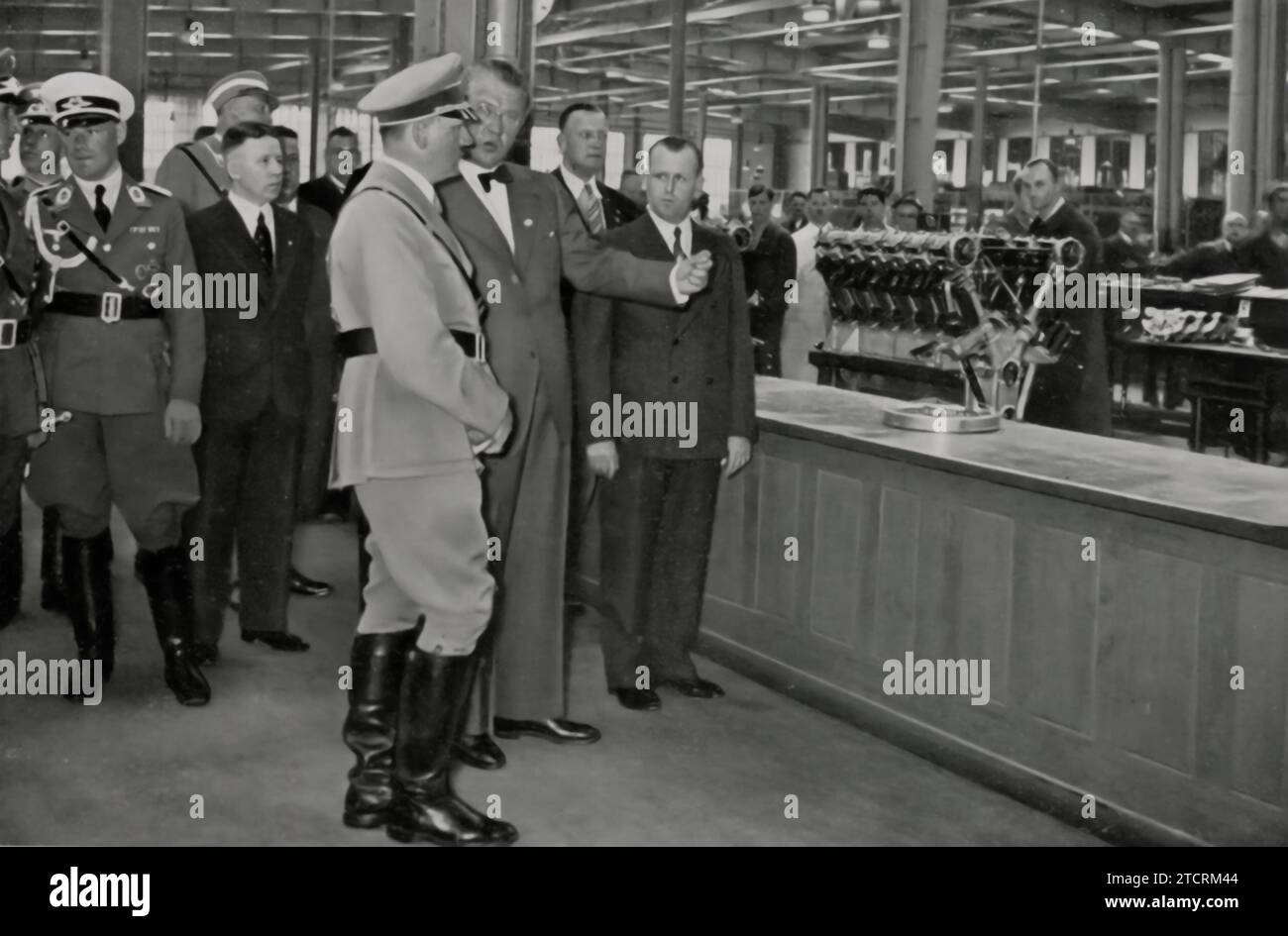 During a visit to the Bavarian Motor Works (BMW), Adolf Hitler is captured engaging with one of Germany's key industrial sectors. This visit underscores his regime's focus on supporting and advancing Germany's automotive and engineering industries. BMW, being a prominent manufacturer, played a significant role in the industrial strategy of Nazi Germany, particularly in terms of military vehicle production. Hitler's presence at the facility symbolizes the Nazi government's commitment to industrial growth and the mobilization of resources for its economic and military objectives. Stock Photo