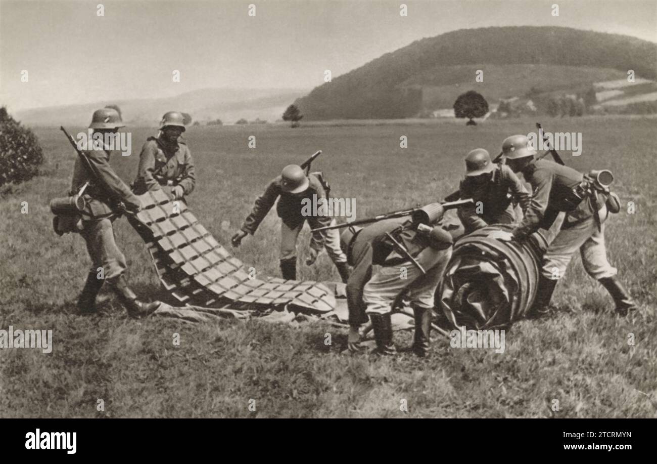 In this scene, German soldiers are shown unfolding an inflatable raft in a field, preparing for a water-based training exercise. Such exercises were common practice for soldiers during World War II, particularly for those involved in amphibious operations or riverine warfare. The ability to swiftly deploy and manage inflatable rafts was crucial for crossing water bodies, conducting reconnaissance, or even launching surprise attacks. Stock Photo