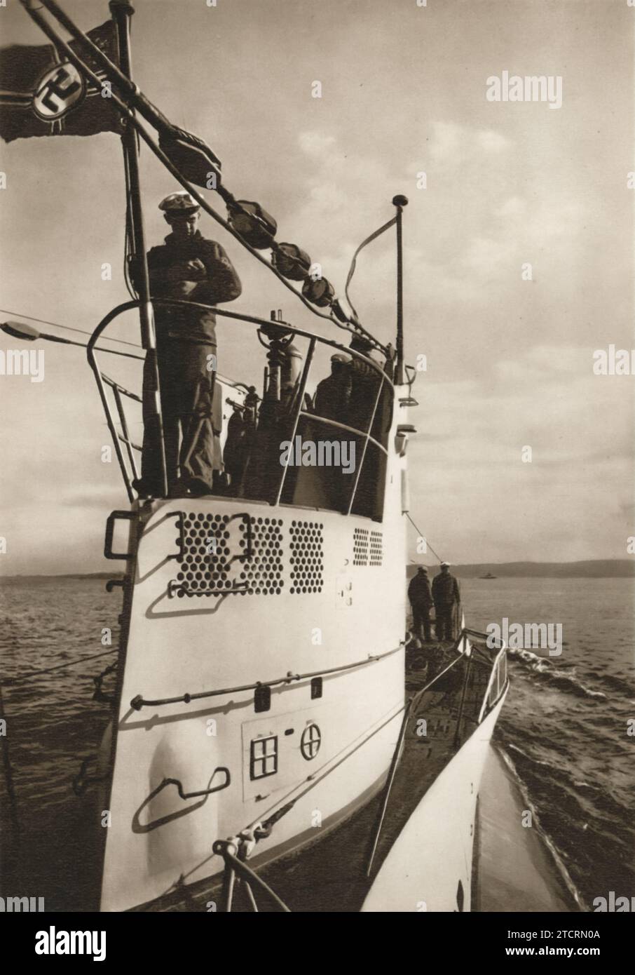 The image captures a striking view of the tower of a German submarine, with several naval soldiers standing atop it as the vessel navigates through open waters. This submarine was part of the Kriegsmarine, Germany's naval force during World War II, renowned for its extensive submarine fleet. These submarines, often referred to as U-boats, played a pivotal role in naval warfare, particularly in disrupting enemy supply lines across the seas. Stock Photo