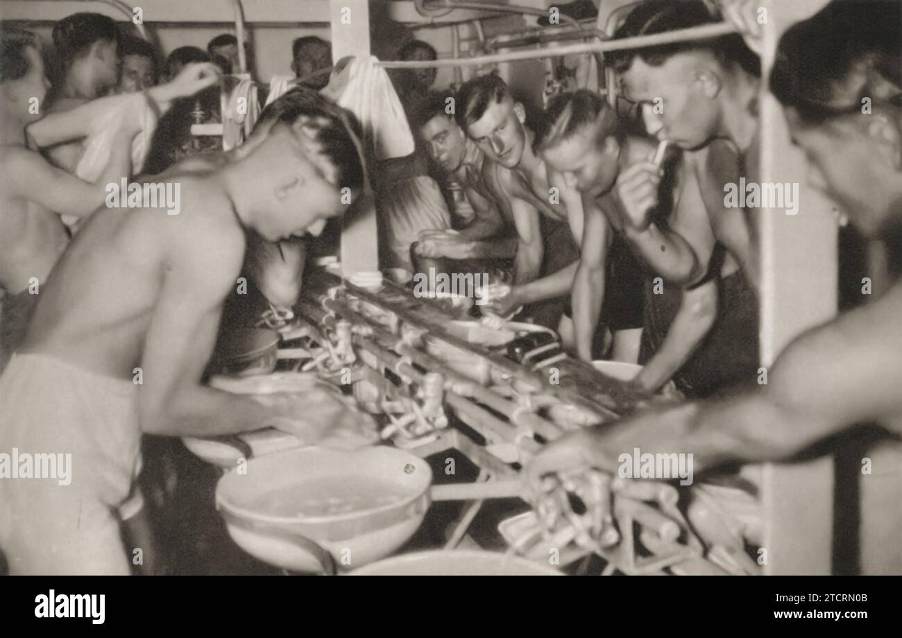 In this image, German Marines, part of the Kriegsmarine, are seen performing their daily routines of washing and brushing their teeth. The photograph highlights the conditions aboard naval vessels during World War II, where space was often limited, but cleanliness and personal hygiene were maintained with military precision. T Stock Photo