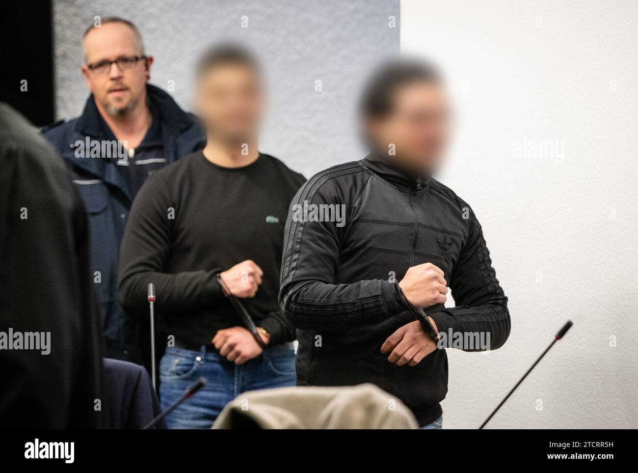 Stuttgart, Germany. 14th Dec, 2023. Two of five defendants are led into a courtroom at the regional court. The Stuttgart Regional Court is holding a trial against five men on charges of attempted manslaughter and causing grievous bodily harm. They allegedly punched and kicked a suspected grenade thrower, who had fled after throwing a hand grenade at a funeral service at a cemetery in Altbach, while he was still in a cab waiting for him and dragged him out of the cab. Credit: --/dpa - ATTENTION: Person(s) has/have been pixelated for legal reasons/dpa/Alamy Live News Stock Photo
