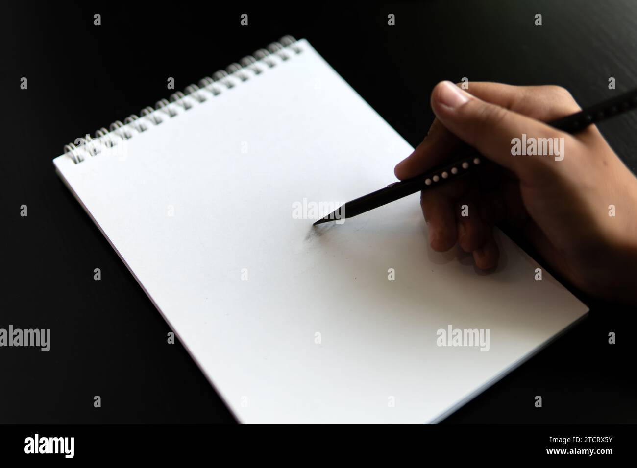 An apple pencil drawing in a notebook and a pencil on a black table. Learning to draw a concept. Stock Photo