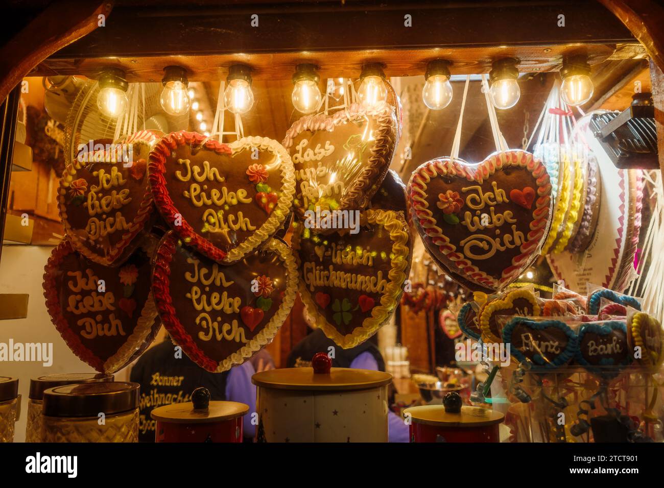 Bonn, Germany - Dec 6, 2023: Decorative gingerbread heart cookies with German phrases at a traditional market stall, warm festive lighting. Stock Photo