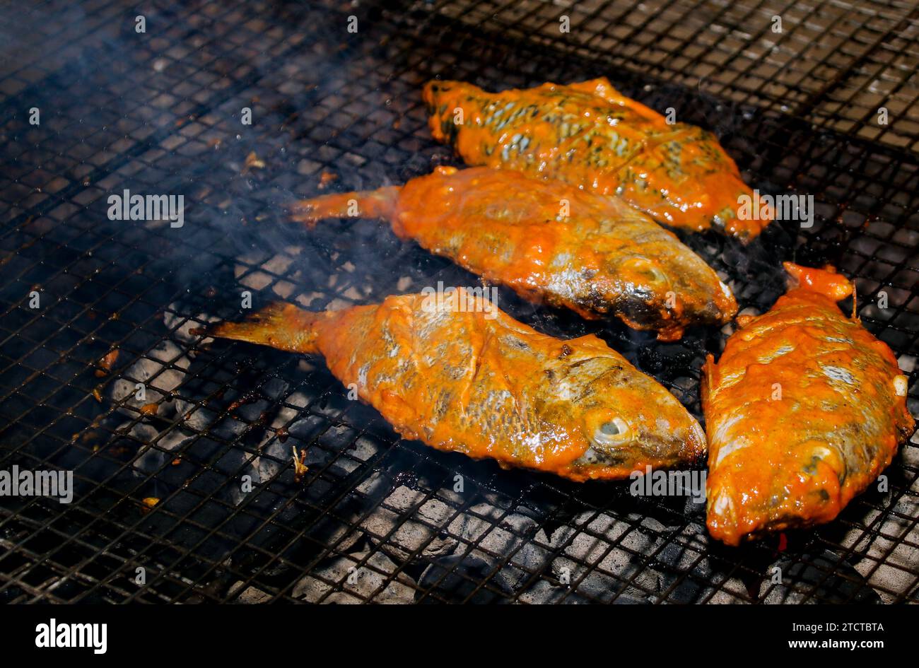 Hot mackerel fish on a grilling pan, with herb spices on coal fire in