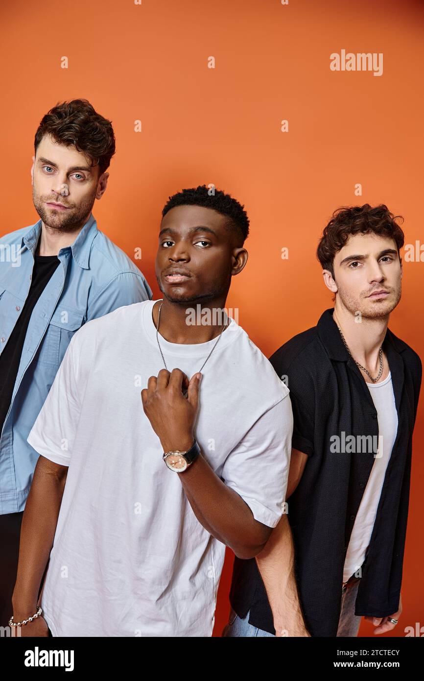 appealing multicultural male models in stylish urban outfits looking at ...