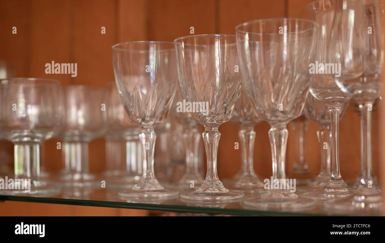 Rows of wine glasses lined up on the glass shelf of a china