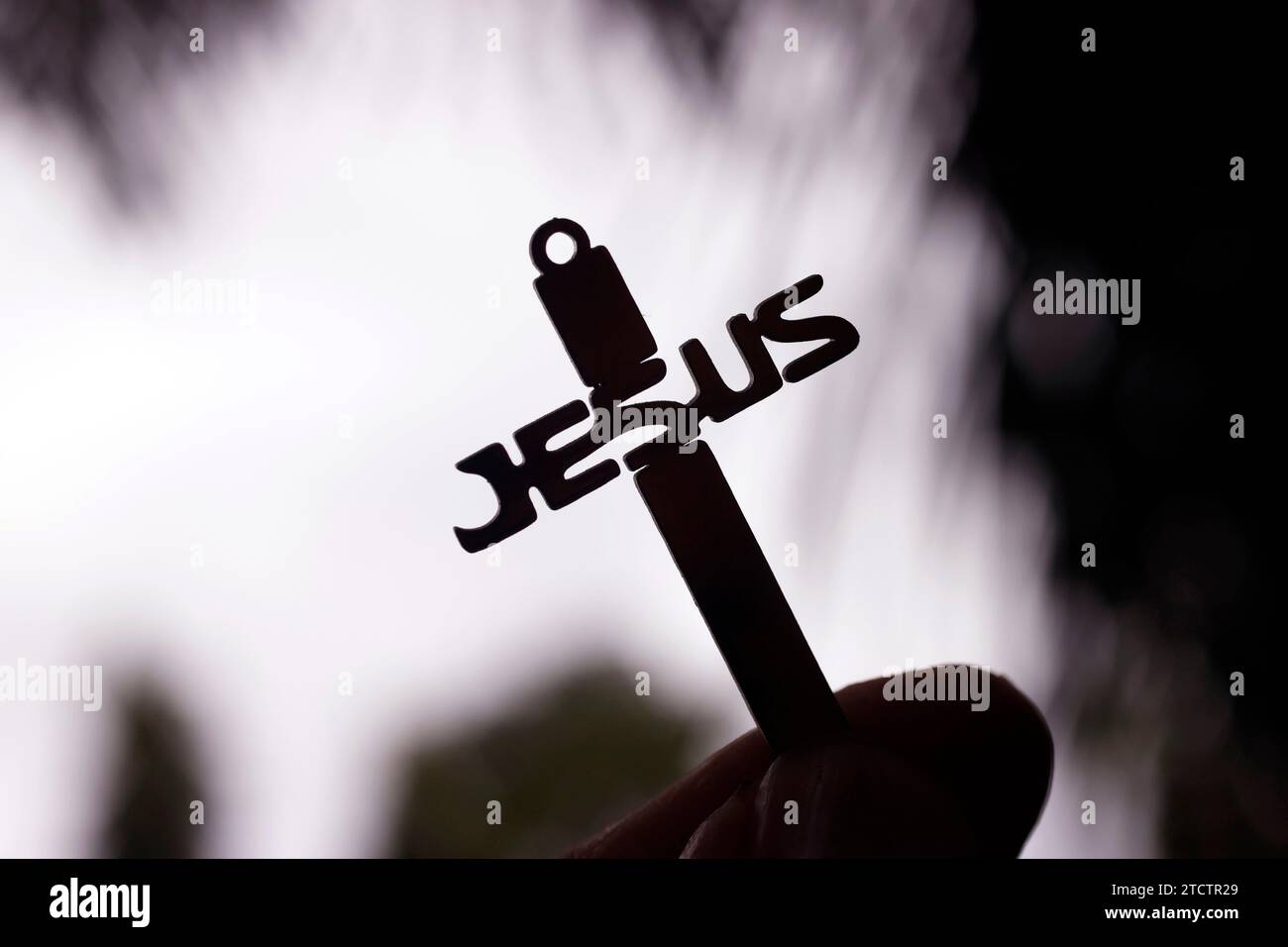 Man holding a christian cross with the name of Jesus against the sky ...