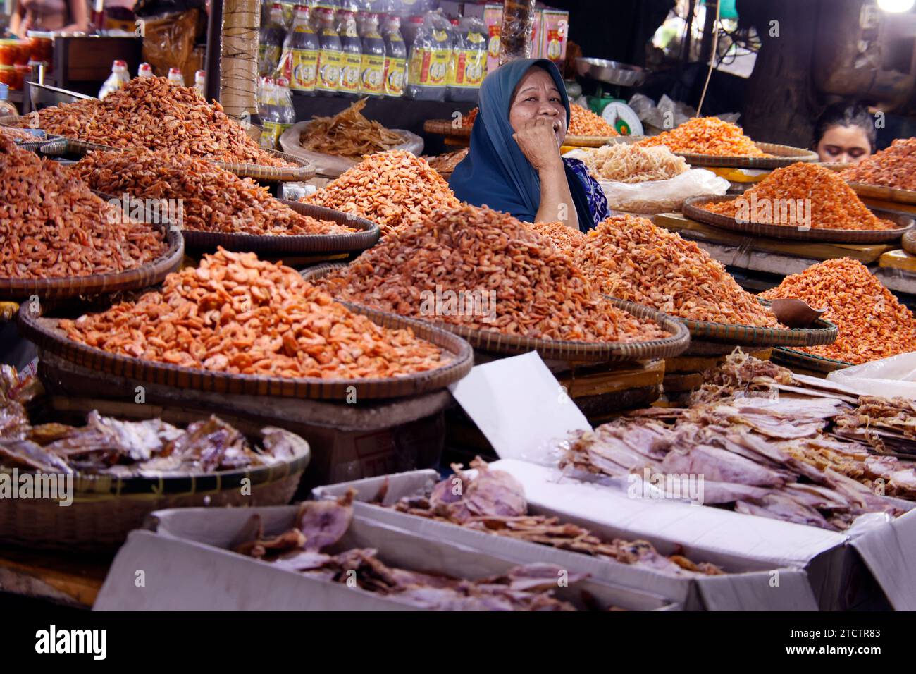 Muslim woman selling dry shrimps and squids at crab market. Stock Photo