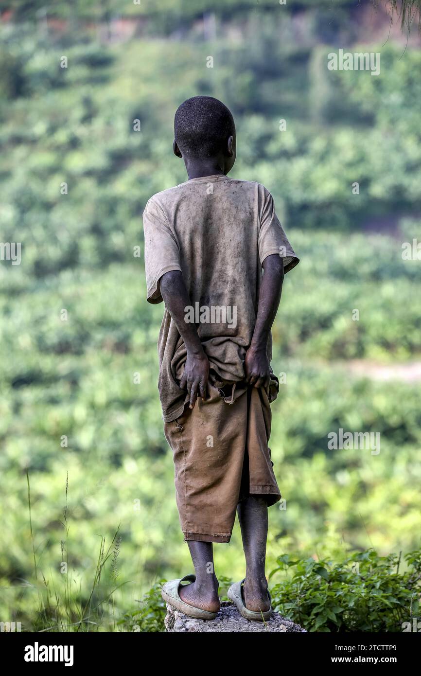Back view of a boy wearing oversized shorts standing on a rock near ...