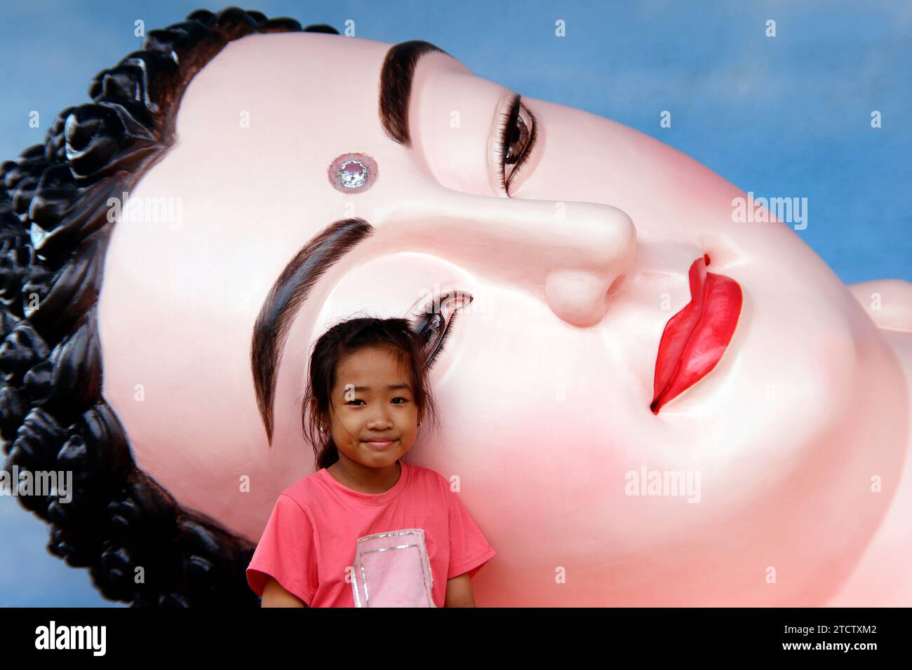 Phuoc Hue buddhist pagoda. Giant gold reclining sleeping Buddha statue with child. Vietnam. Stock Photo