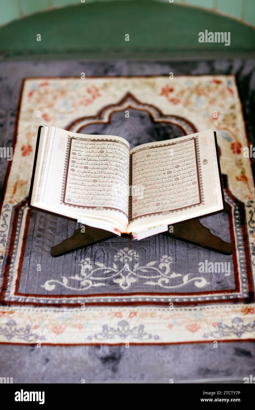 Mubarak mosque. Open Quran in arabic on wood stand. Symbol of Islam