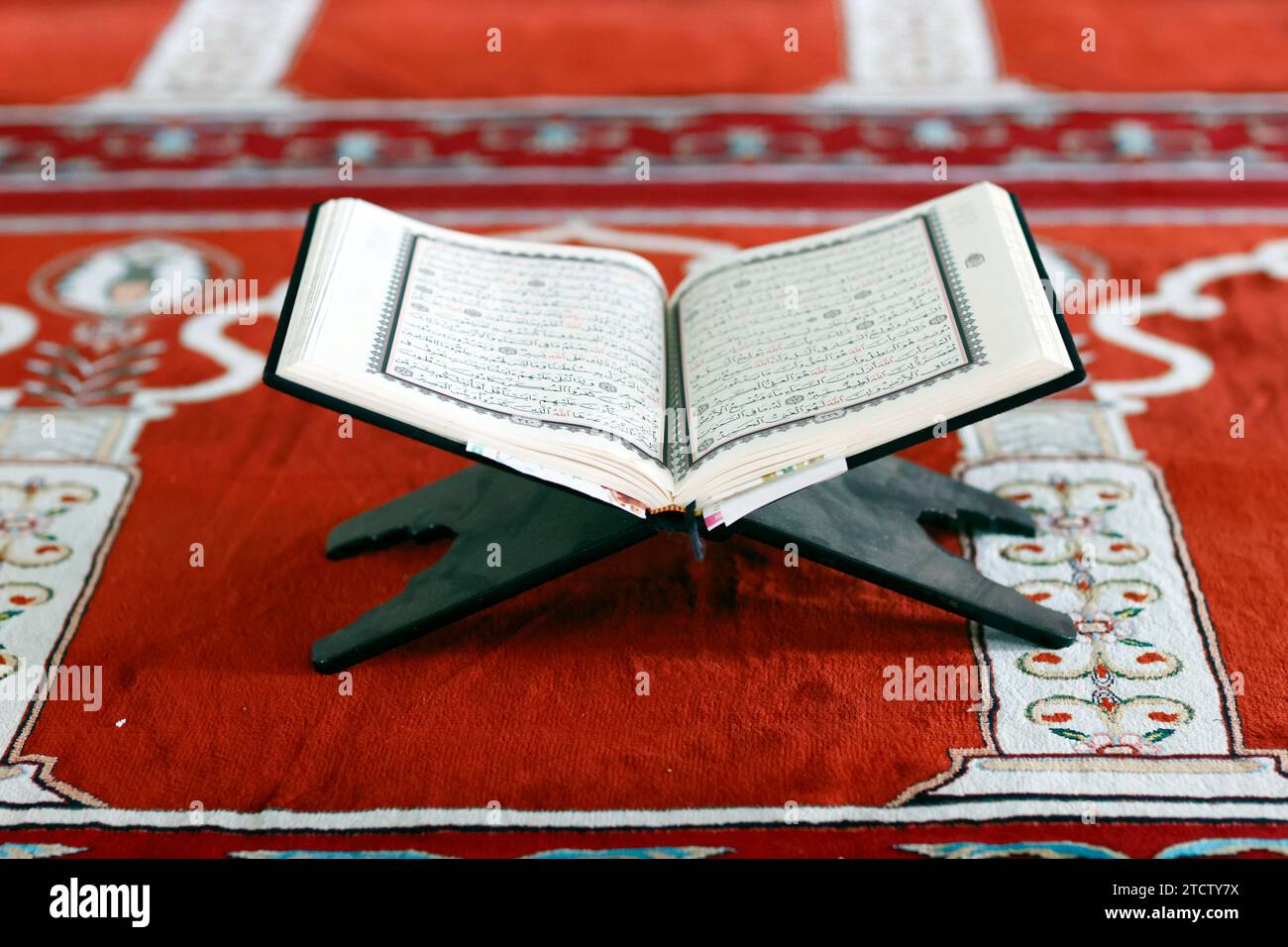 Mubarak mosque. Open Quran in arabic on wood stand. Symbol of Islam