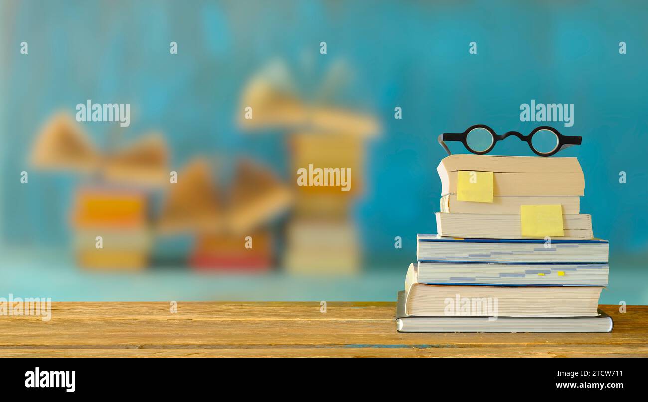stack of books, booksmarks and spectacles, blurred open books in the background.Spring Book fair , inspiration,reading, education, literature concept, Stock Photo