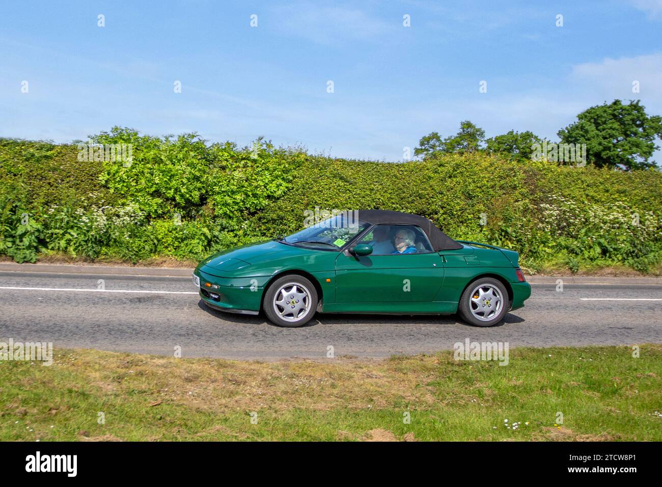 1990 90s green Mazda Miata soft-top convertible; Vehicular traffic, moving vehicles, cars, vehicle driving on UK roads, motors, motoring on the M6 motorway highway UK road network. Stock Photo