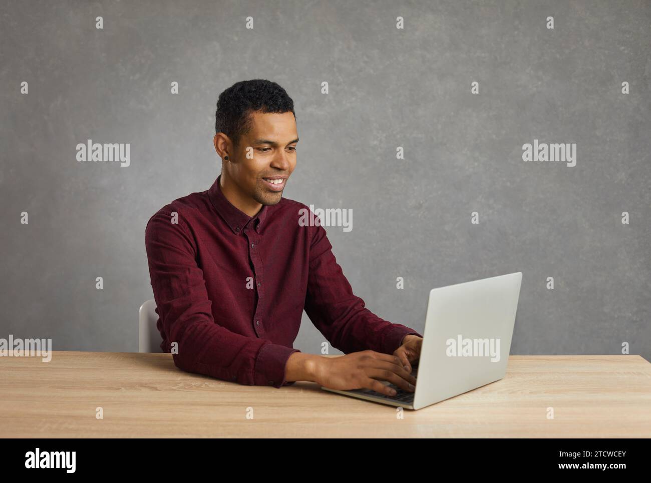 Positive african american programmer creates a new program and encodes while sitting at a laptop. Stock Photo