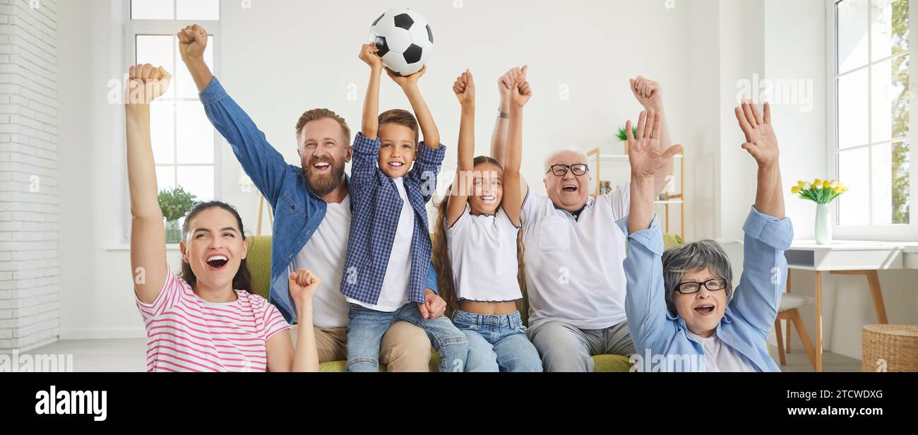 Excited happy family grandparents, parents and children fans watching sport football match on tv. Stock Photo