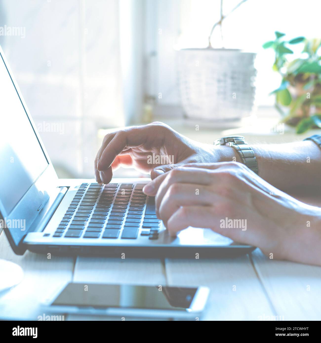 Laptop, phone. Programmer's hands working on laptop keyboard. Stock Photo