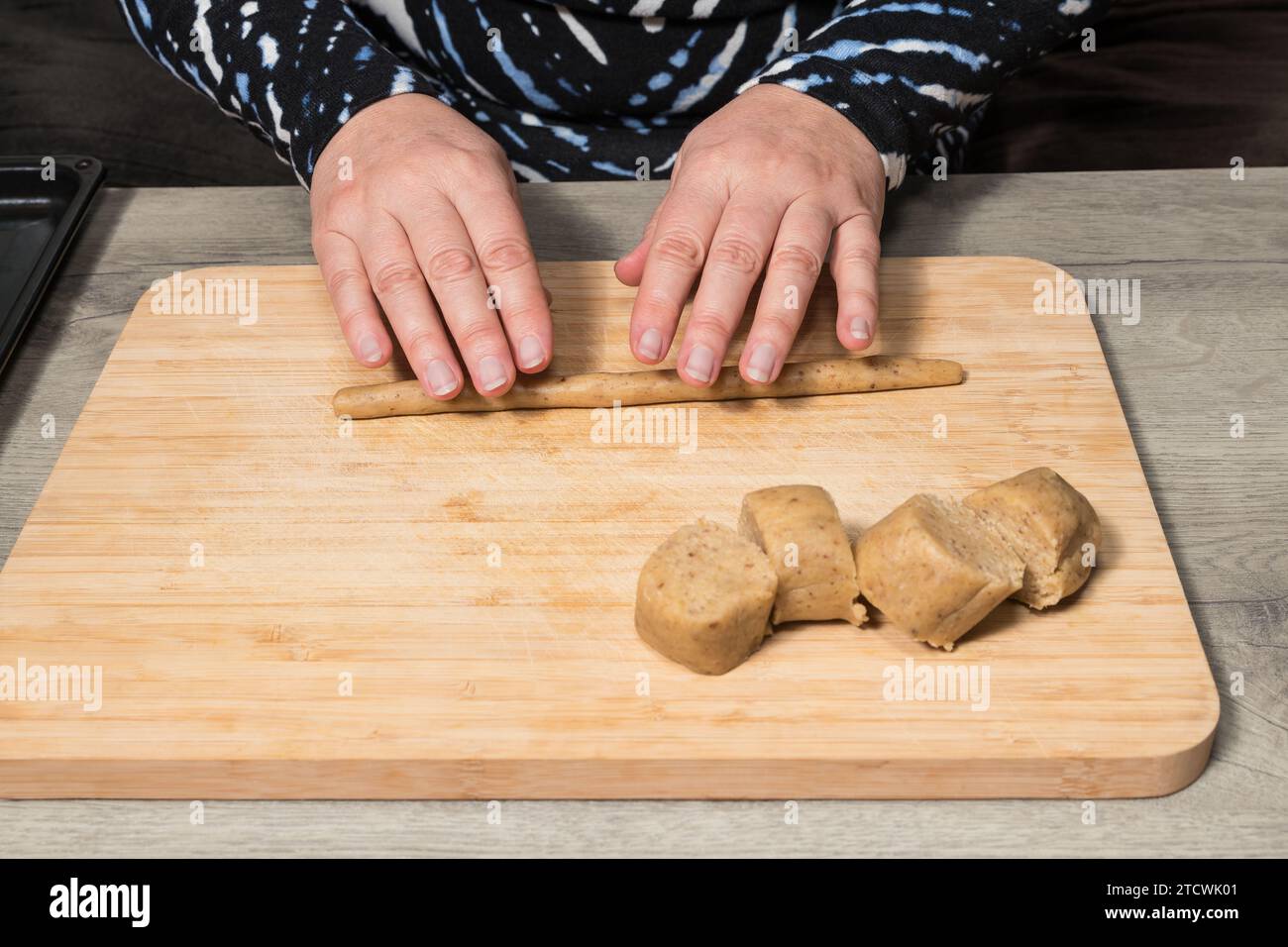 Closeup of human hands working with raw nutty shortbread dough on wood ...