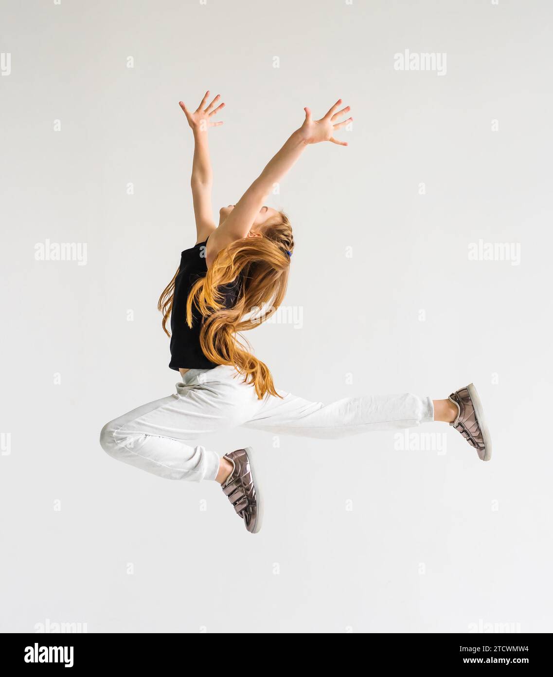 Excited young girl leaping in the air with her hands raised. Sport ...