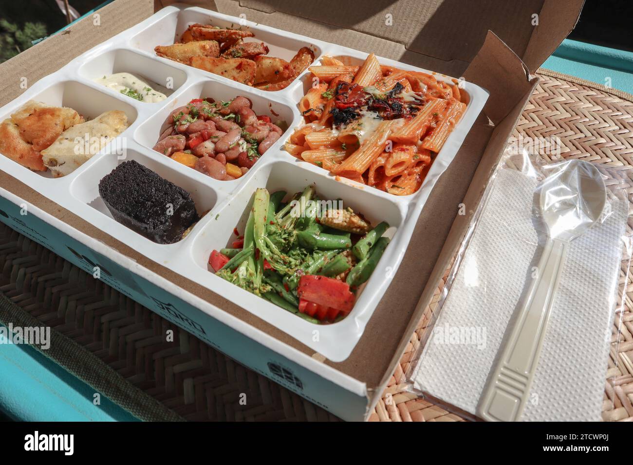 Continental or Americal lunch platter parcel.Pasta, crunchy salad, brownie, Potato wedges with dip Stock Photo