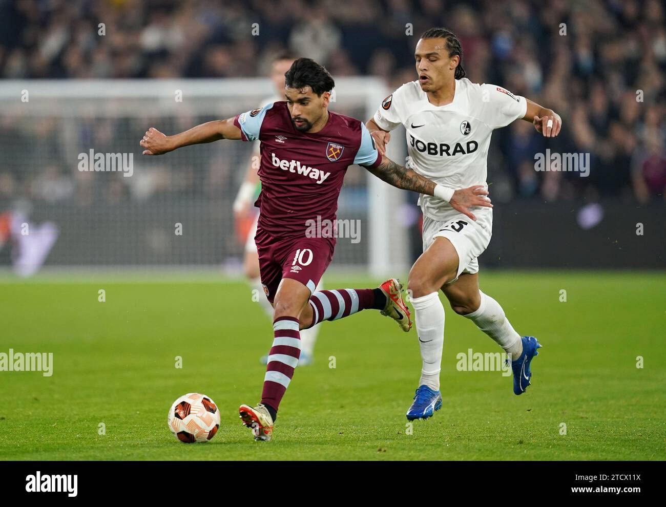 West Ham United's Lucas Paqueta (left) and Freiburg's Kiliann Sildillia battle for the ball during the UEFA Europa League group A match at London Stadium, London. Picture date: Thursday December 14, 2023. Stock Photo