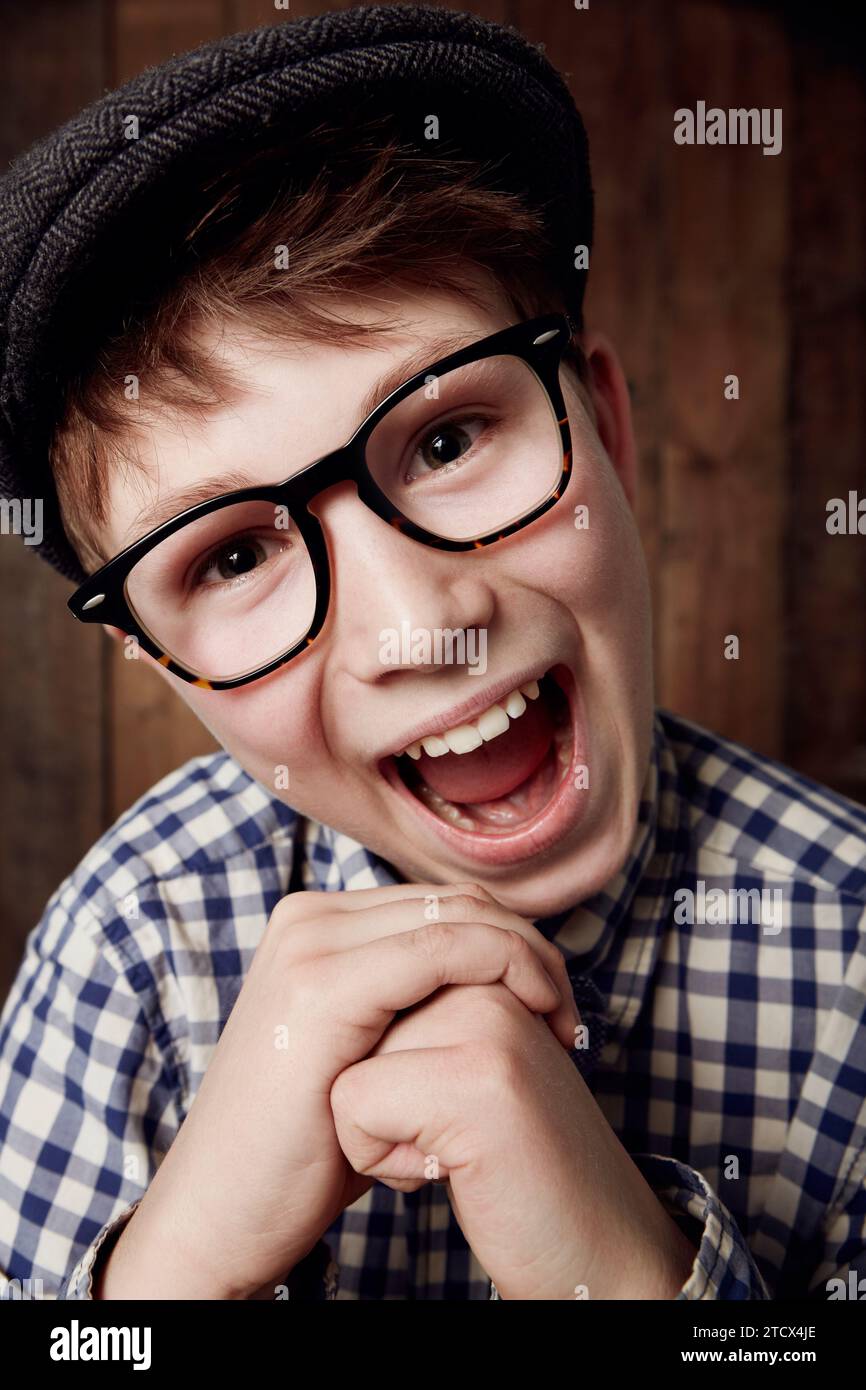 Glasses, portrait and happy for boy in funny comic and vintage fashion in eyewear by wooden background. Child, face or laughter for comedy or retro Stock Photo