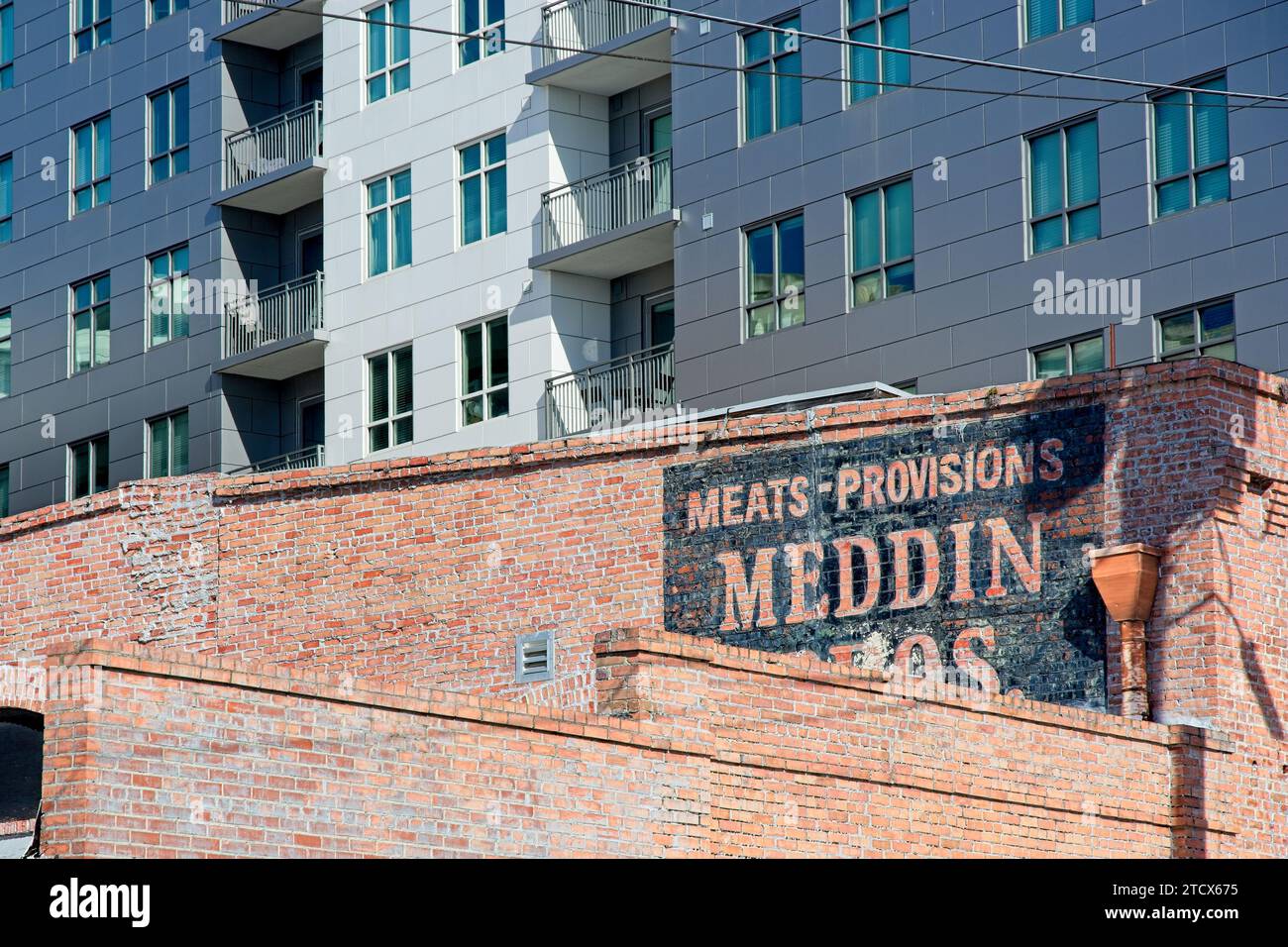 Contemporary midrise apartment building behind weathered brick commercial warehouse in downtown