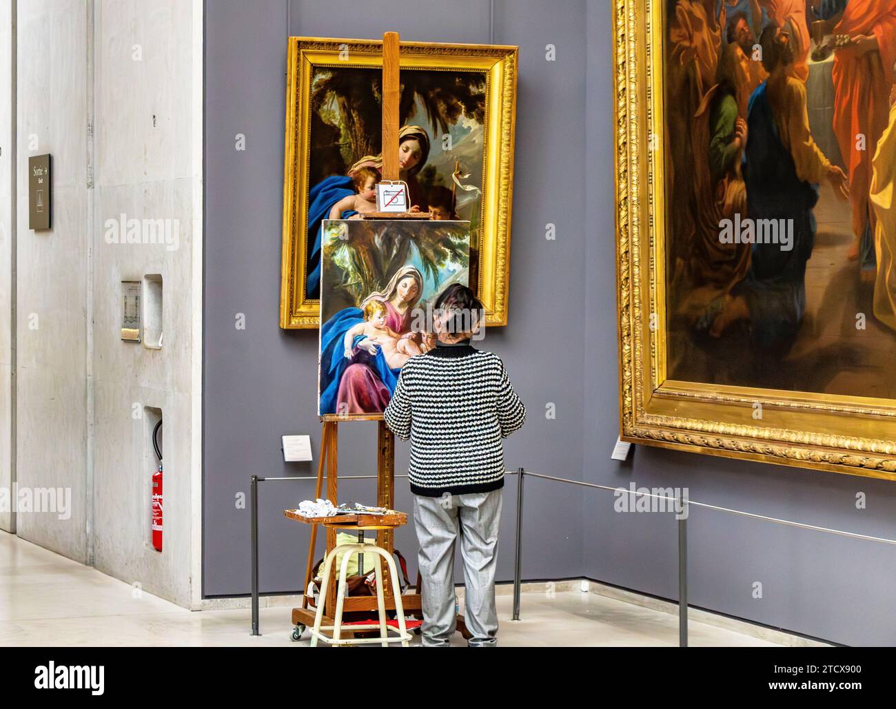 A female artist copying a painting in a gallery inside The Louvre ...