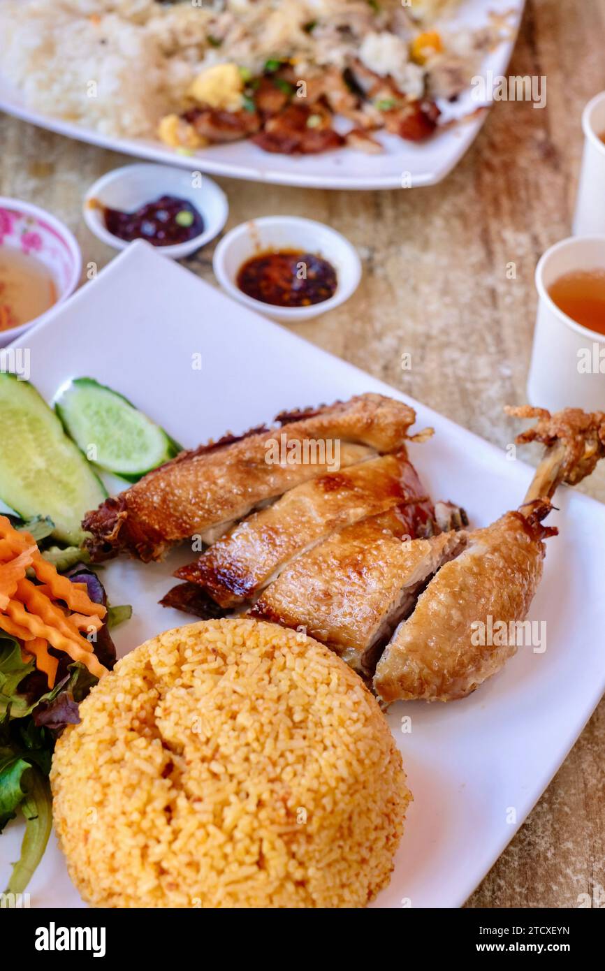 Crispy-skin chicken Maryland with tomato rice and combination broken rice with pork chop, condiments and tea at a Vietnamese restaurant in Sydney Stock Photo