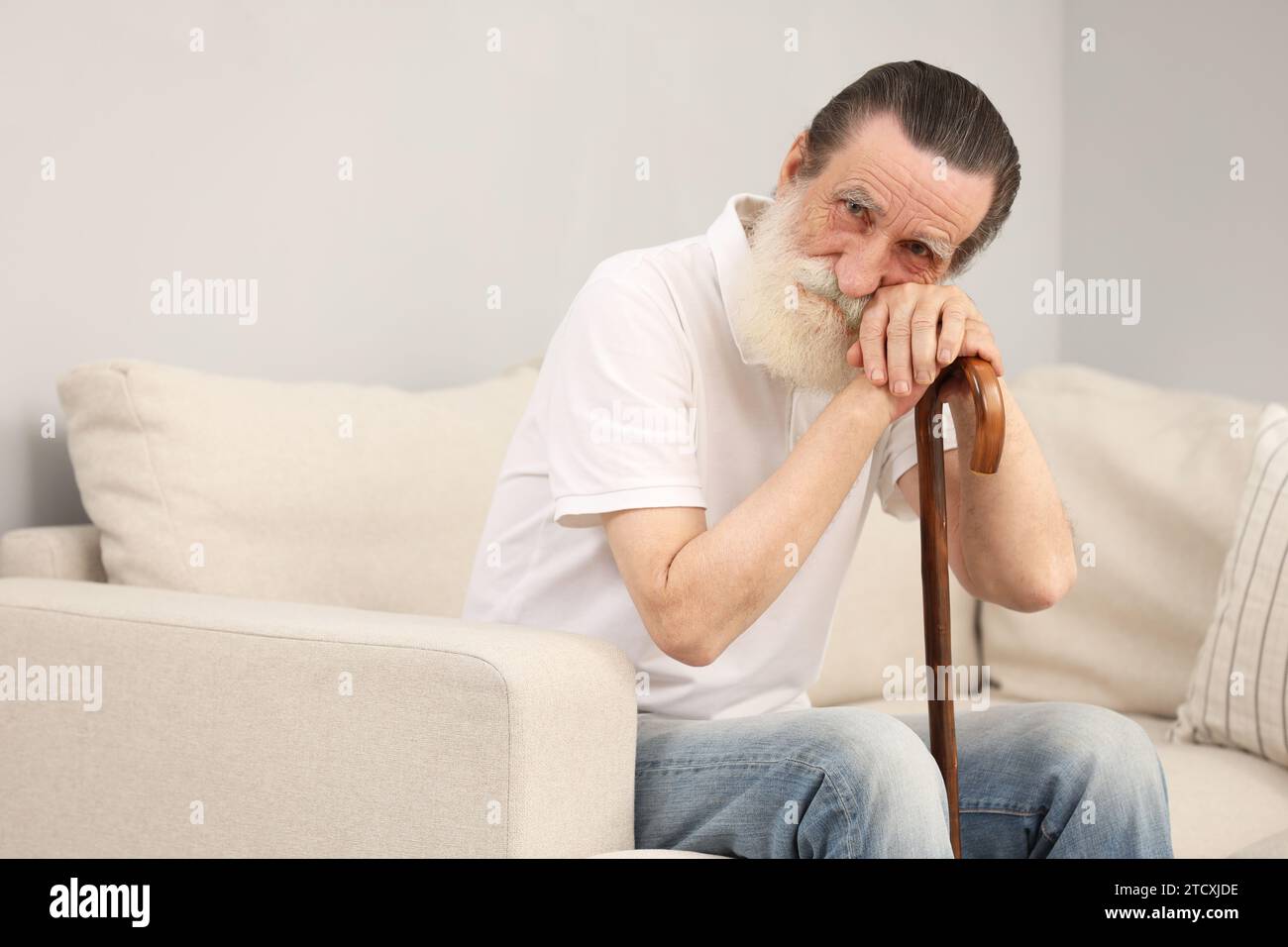 Senior man with walking cane on sofa indoors Stock Photo - Alamy