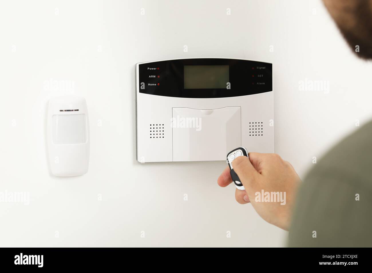Home security system. Man using alarm key fob indoors, closeup Stock Photo