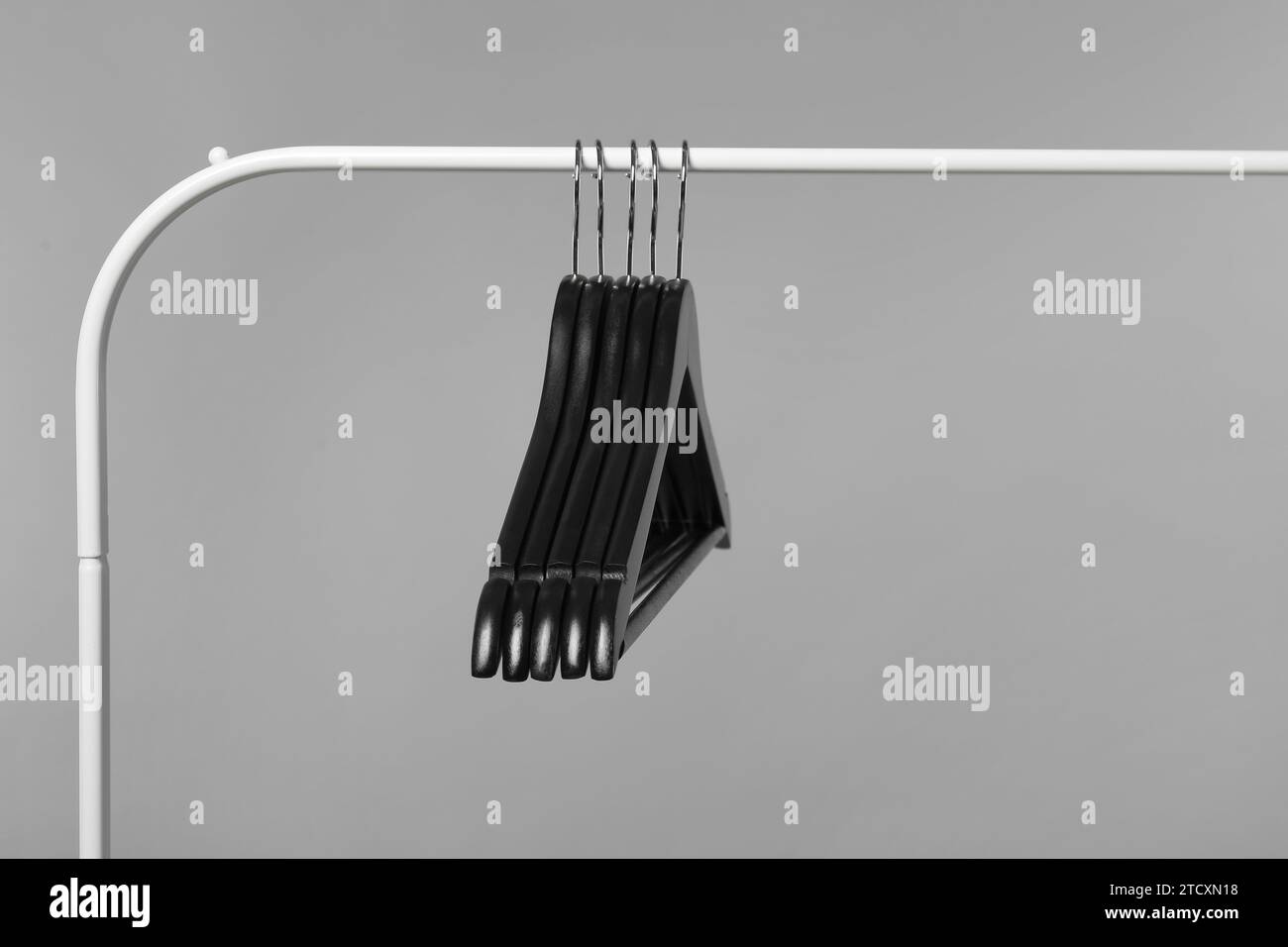 Black clothes hangers on rack against grey background Stock Photo Alamy