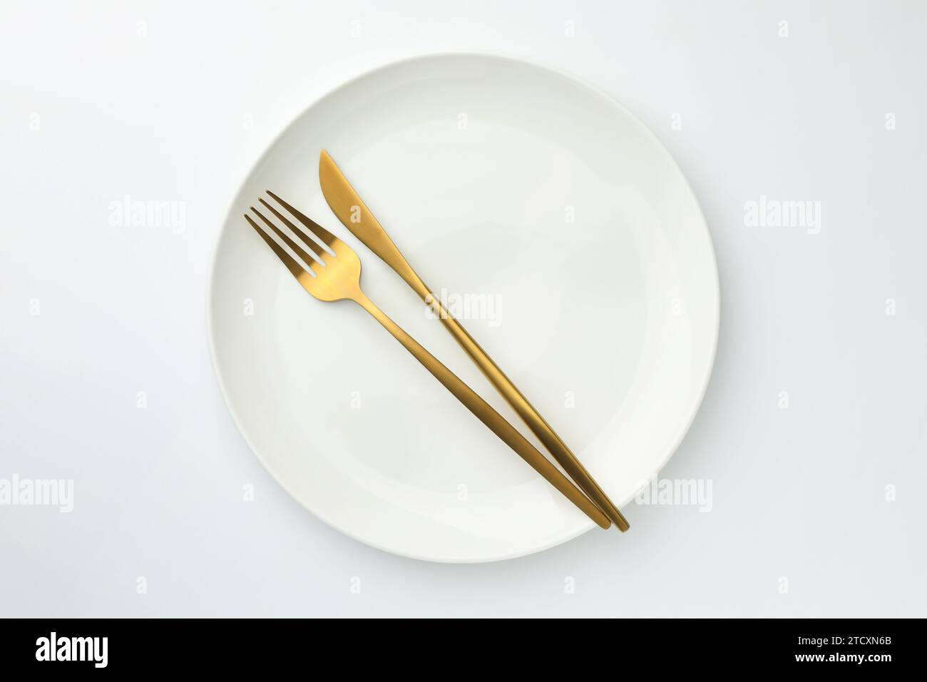 Plate, fork and knife on white background, top view Stock Photo - Alamy