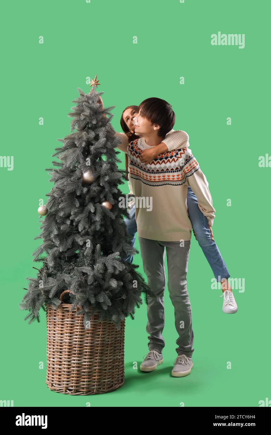 Cute girl and her brother decoration Christmas tree on green background ...