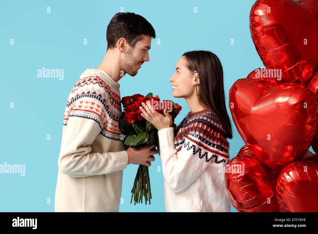 Beautiful young couple with bouquet of red roses and heart shaped air ...