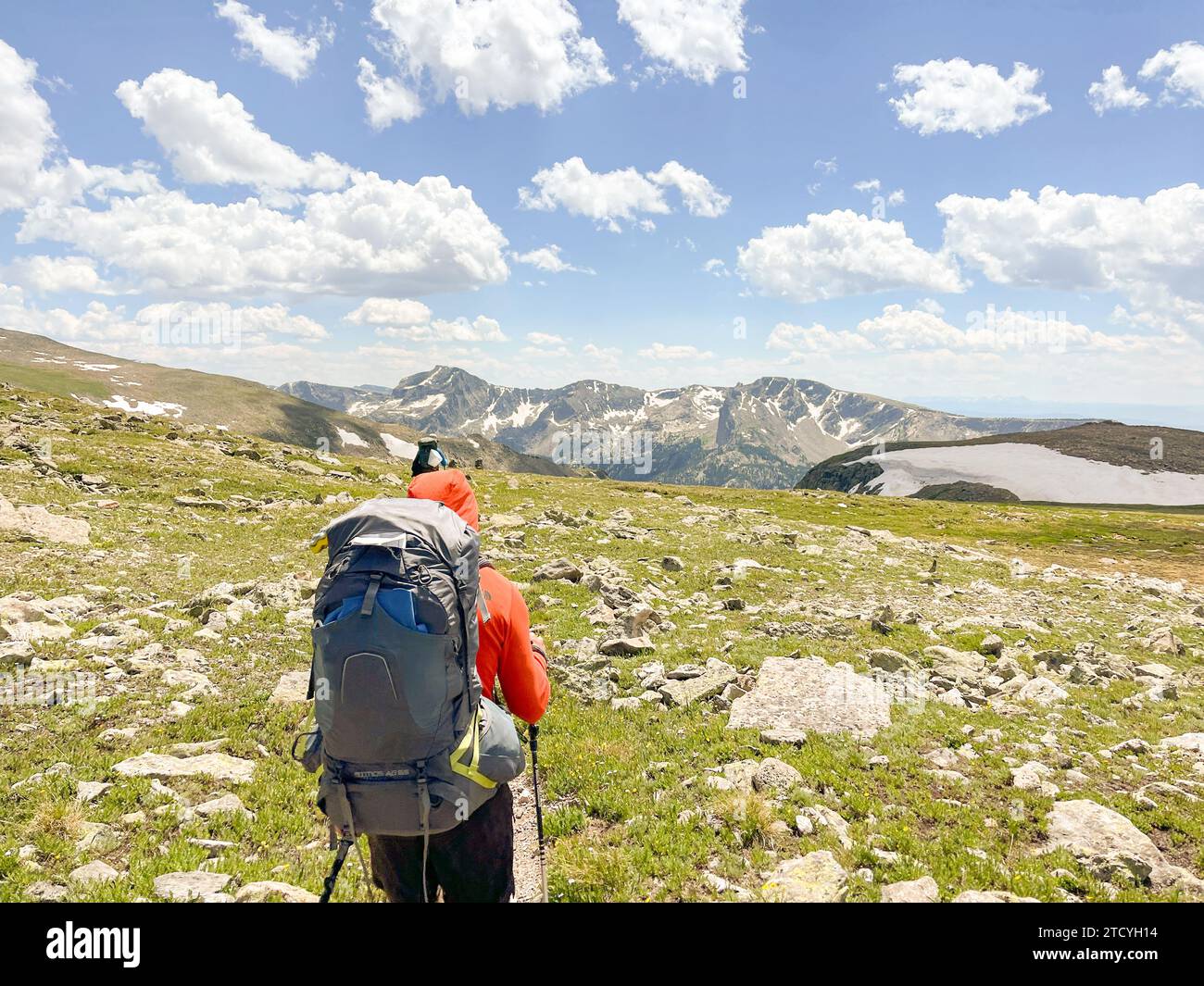Two hikers follow a trail in Rocky Mountain National Park, their Two hikers follow a trail in Rocky Mountain National Park, their