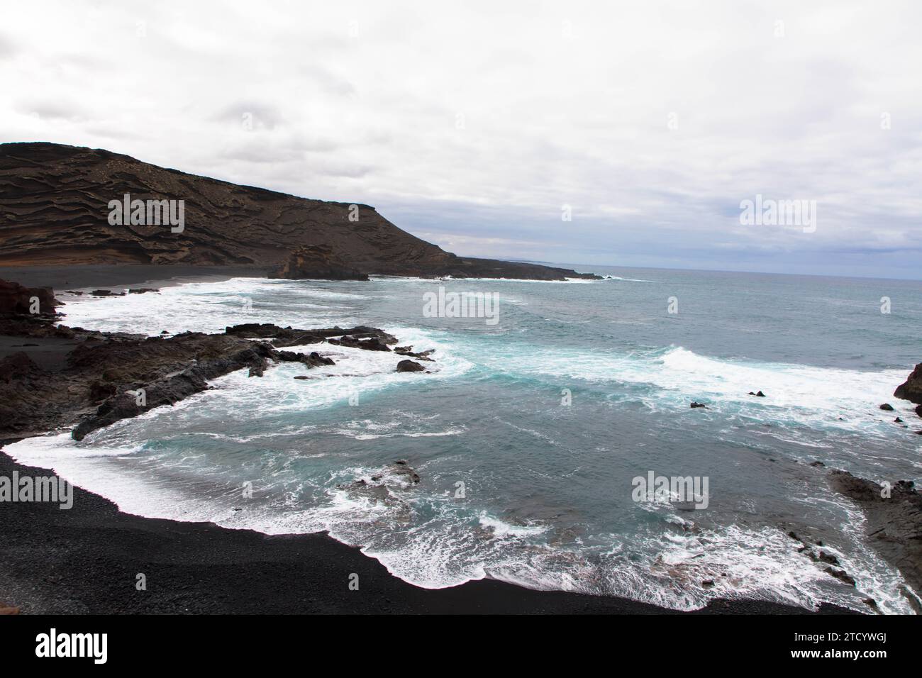 Panoramic view of Playa El Golfo volcanic beach and rocky coast on a windy day. Seen from the Charco de los Clicos viewpoint. Lanzarote, Canary Island. Stock Photo
