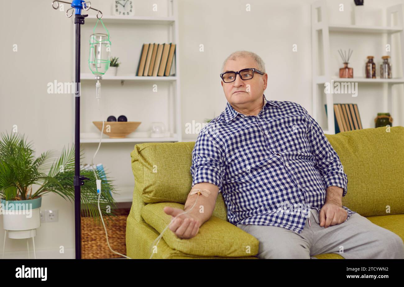 Senior man sitting on sofa and getting intravenous medicine infusion