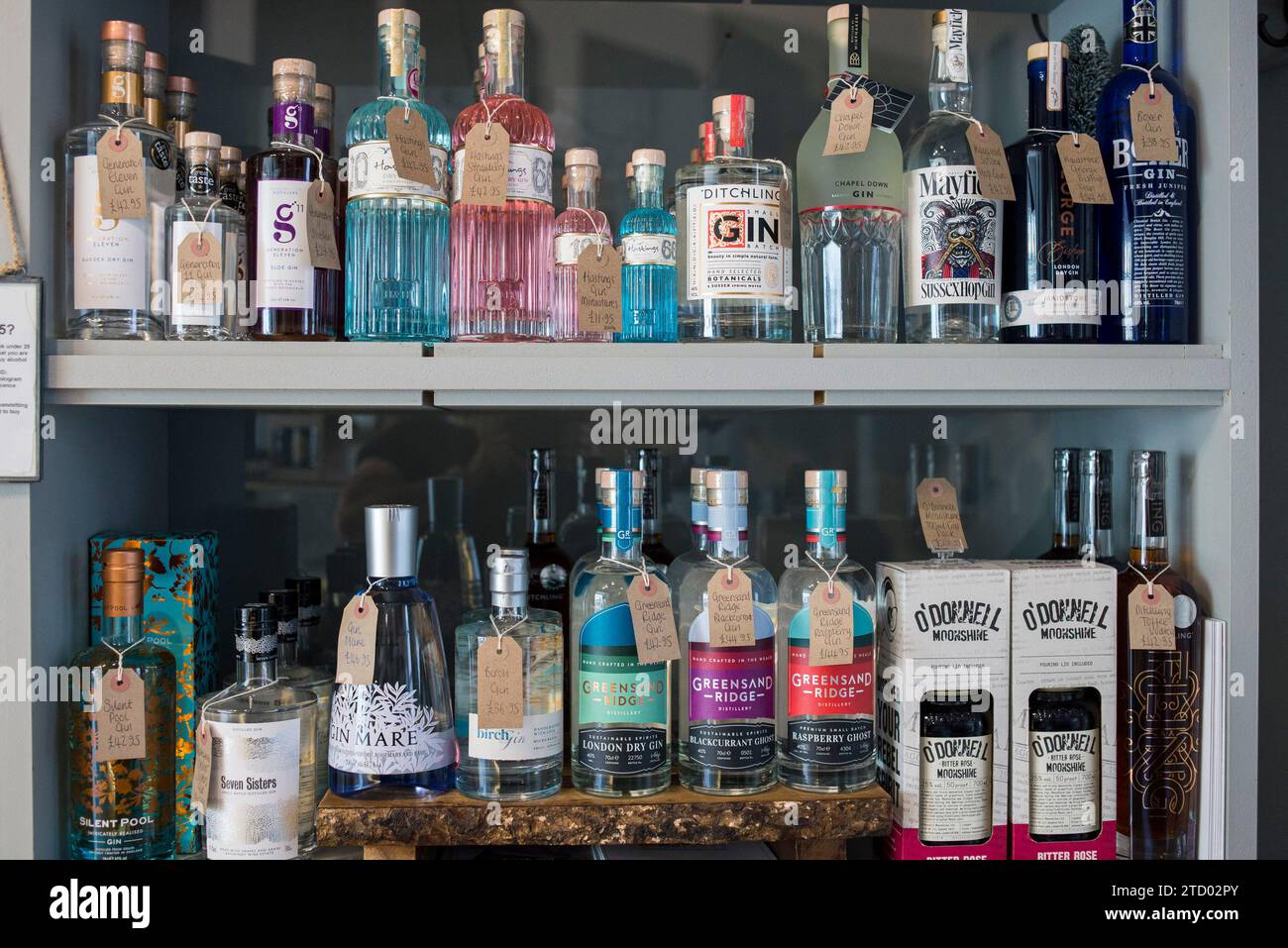 Shelves with high end bottles of wine and gin on display for sale in a local deli shop Stock