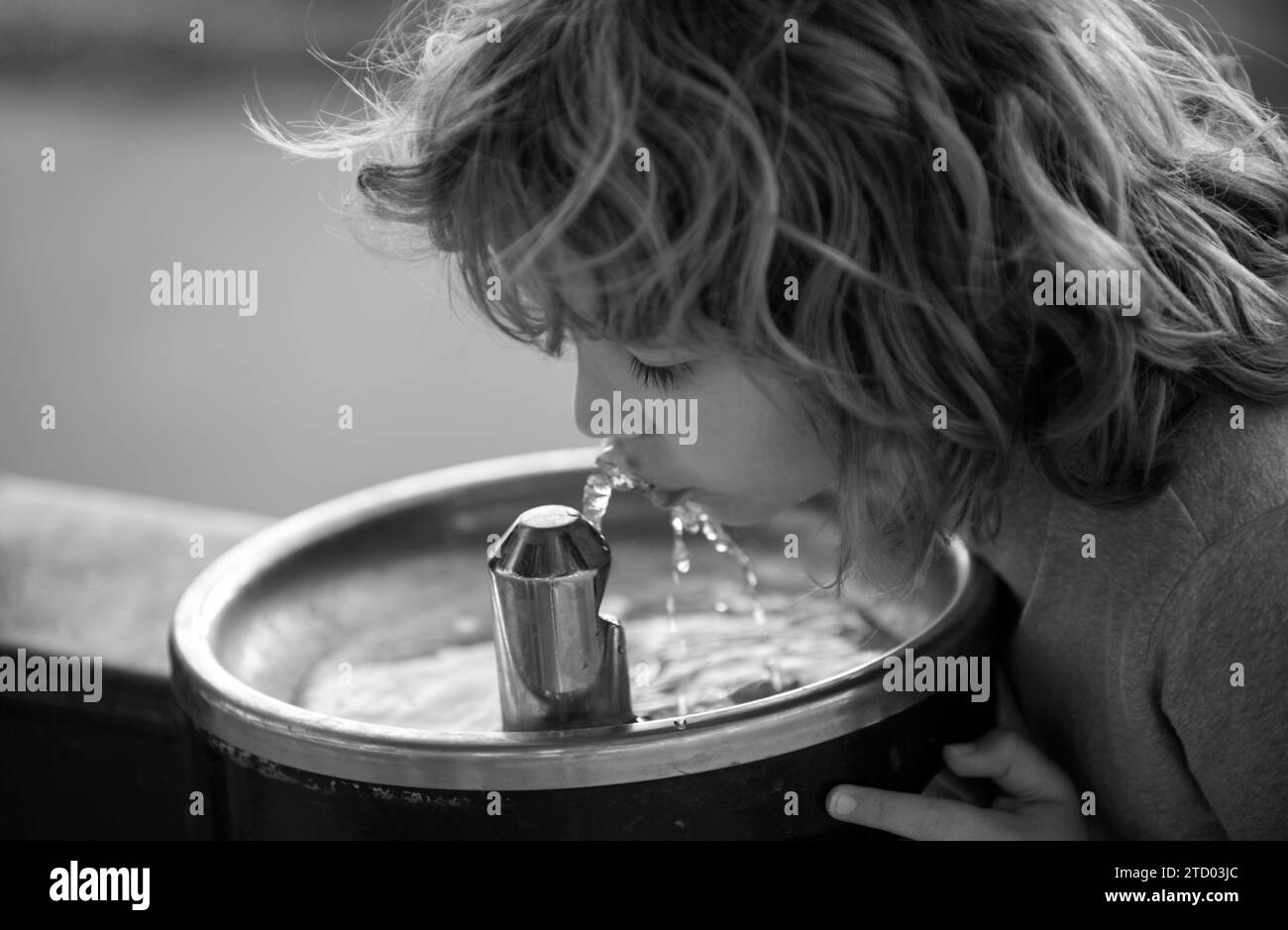Face close up portrait of child drinking water from tap or water outdoor in park. Close up portrait of kid drinking. Thirsty child. Stock Photo