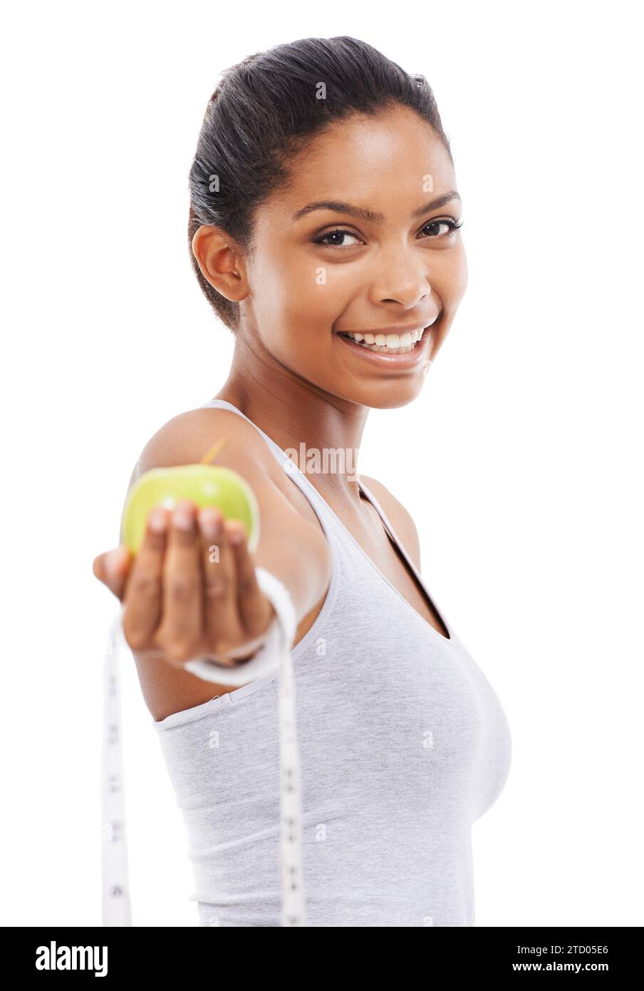 Happy woman, portrait and lose weight with a measuring tape and apple in white background or studio. Indian, model and healthy food for results in Stock Photo