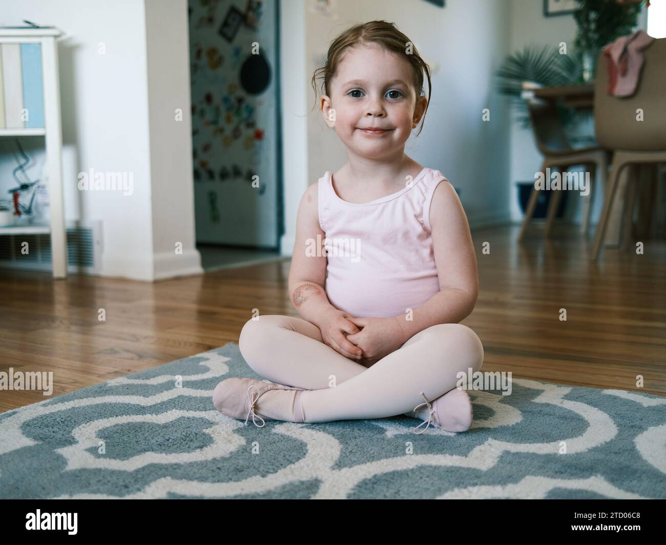 Happy toddler in ballet outfit smiling in living room Stock Photo