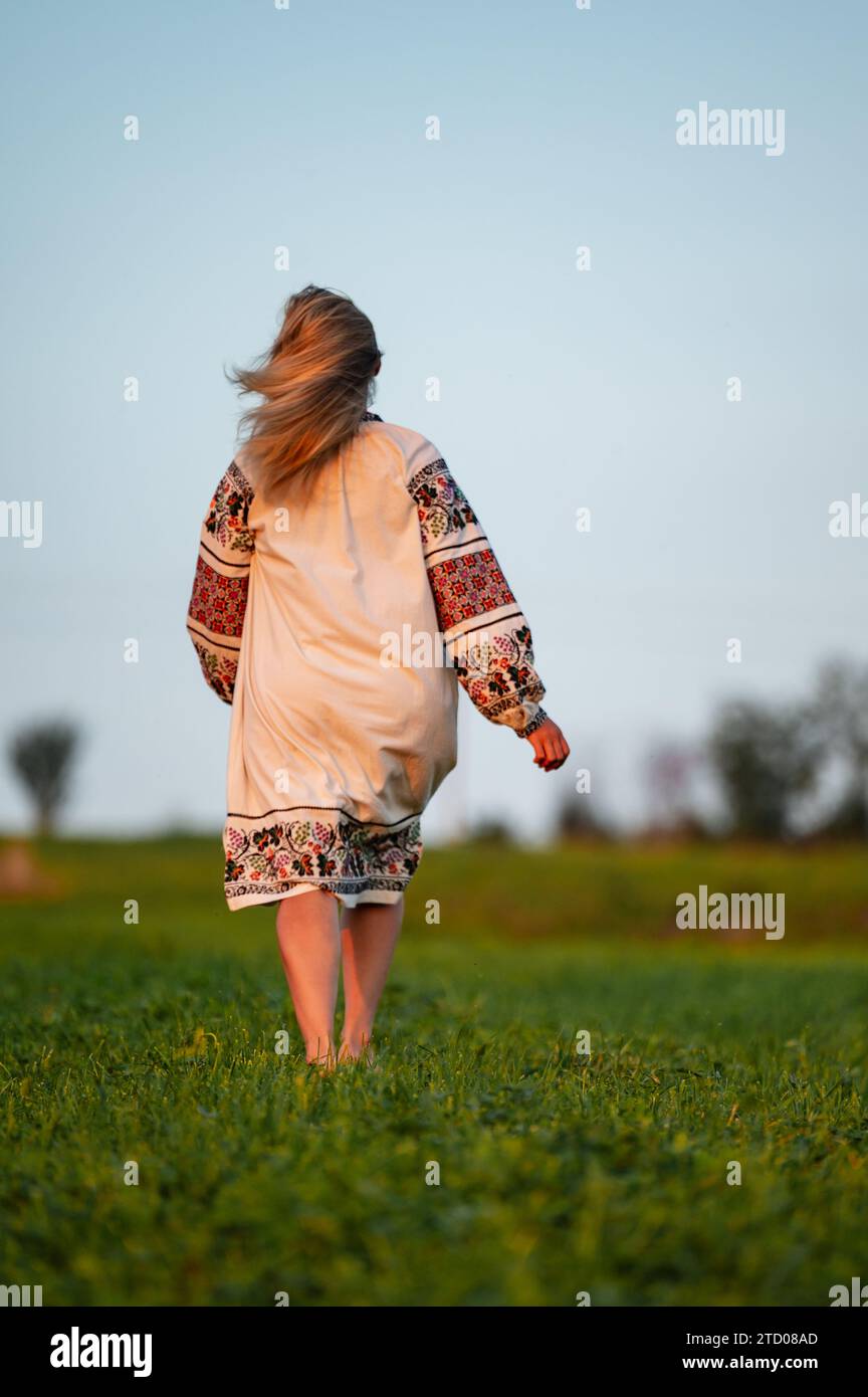 Embroidered and unique petticoat, a girl walks barefoot in the field in an embroidered shirt, Ukrainian clothes and traditions. Stock Photo