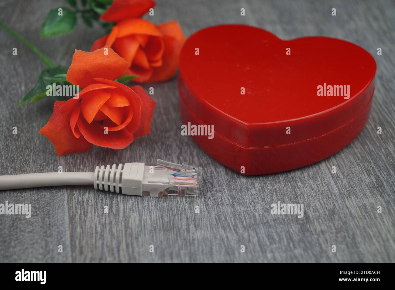 red heart and red roses with grey internet cable, symbolic image of love online Stock Photo