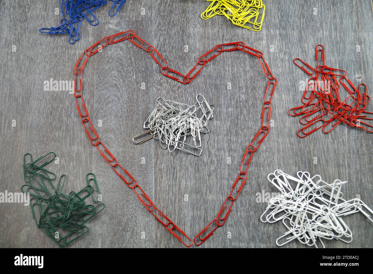 colourful paper-clips, the red layed in heart-shape, love in the office Stock Photo