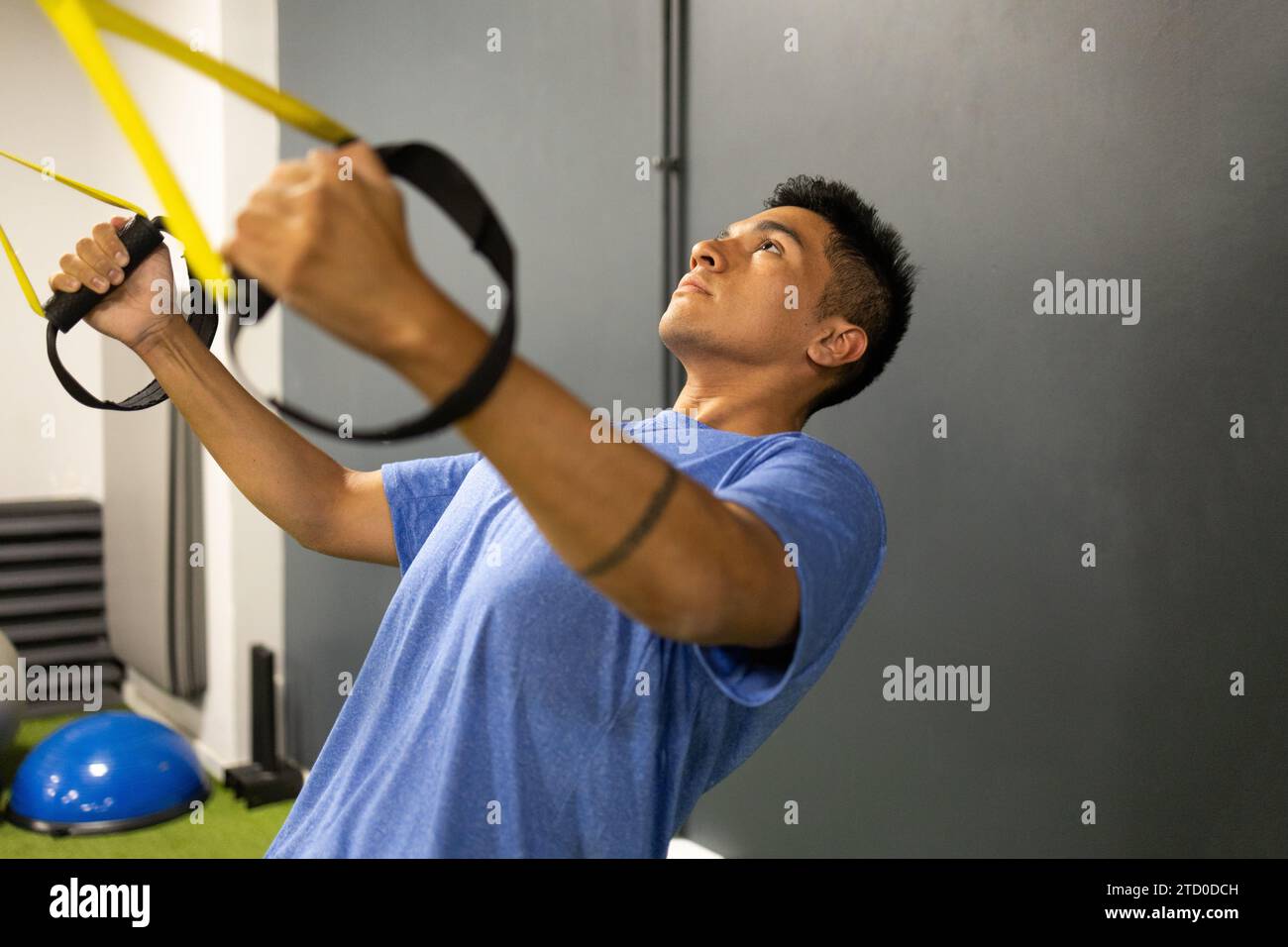 A focused man performing suspension training exercises with TRX bands ...